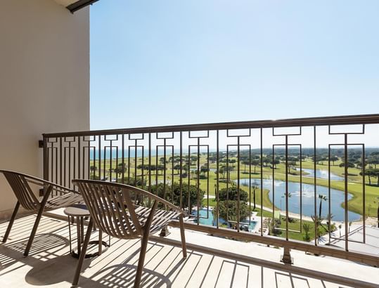 Golf course view from balcony with two chairs in Superior Room Sea View at Cullinan Belek