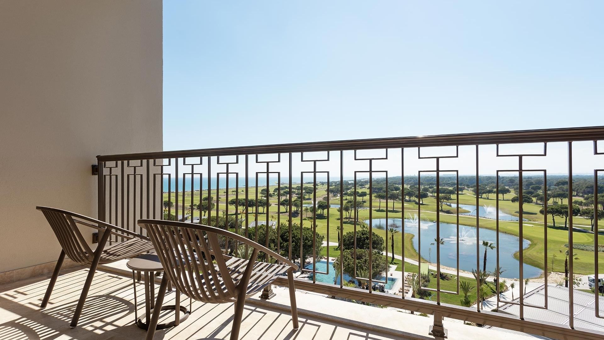 Golf course view from balcony with two chairs in Superior Room Sea View at Cullinan Belek