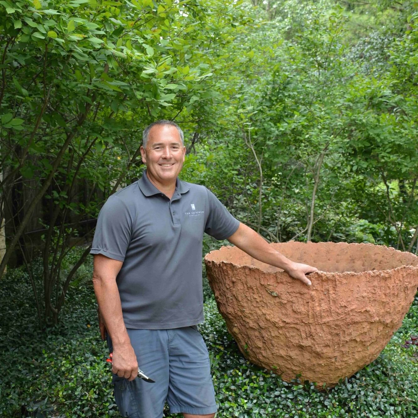 A man standing next to a large clay pot near Umstead Hotel and Spa