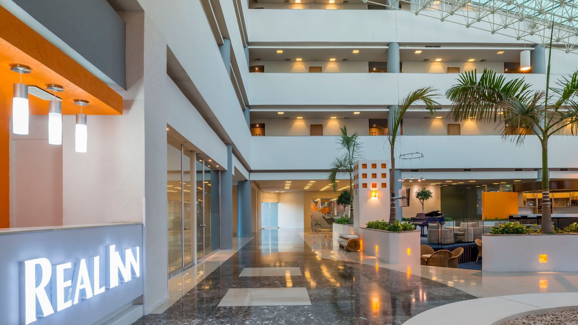 Interior lobby featuring palm trees, polished floors, and a modern reception area at Real Inn Nuevo Laredo