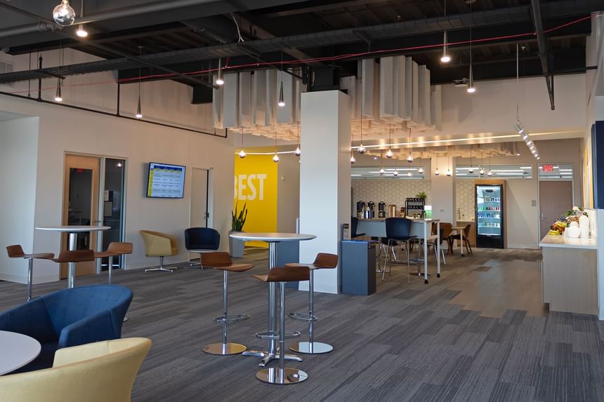 Michigan Ross Conference Center modern office space with tables, chairs, a yellow wall, and a refrigerator.