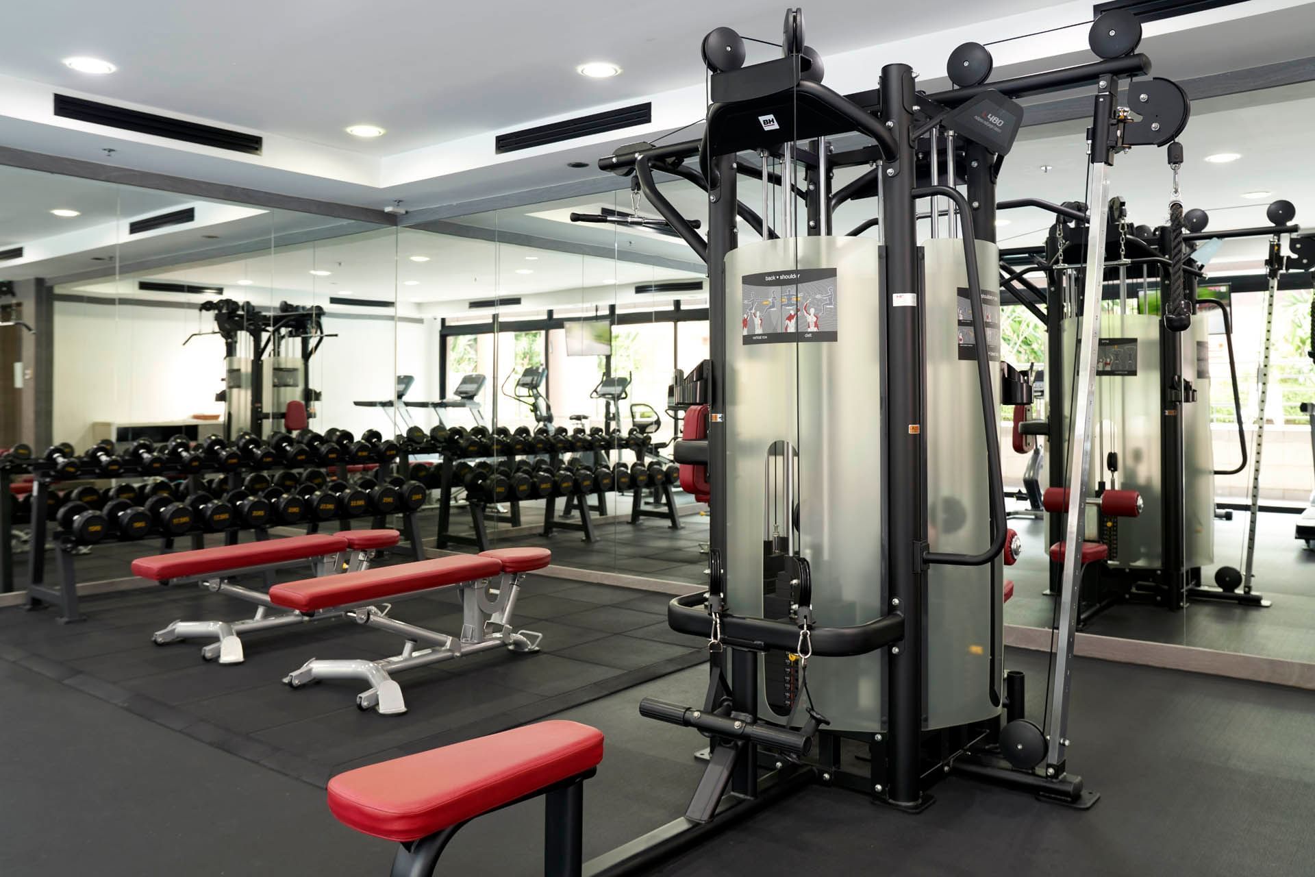 Contemporary gym with benches, dumbbells, a multifunctional machine and natural light at Orchard Grand Court