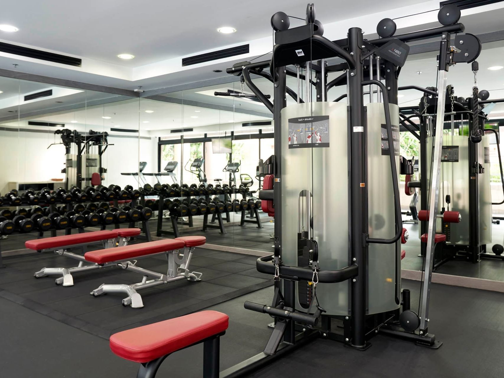 Contemporary gym with benches, dumbbells, a multifunctional machine and natural light at Orchard Grand Court
