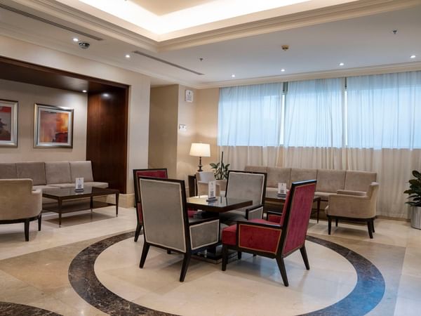 Elegant lounge area with couches, chairs, and a round table at Saja by Warwick Makkah.