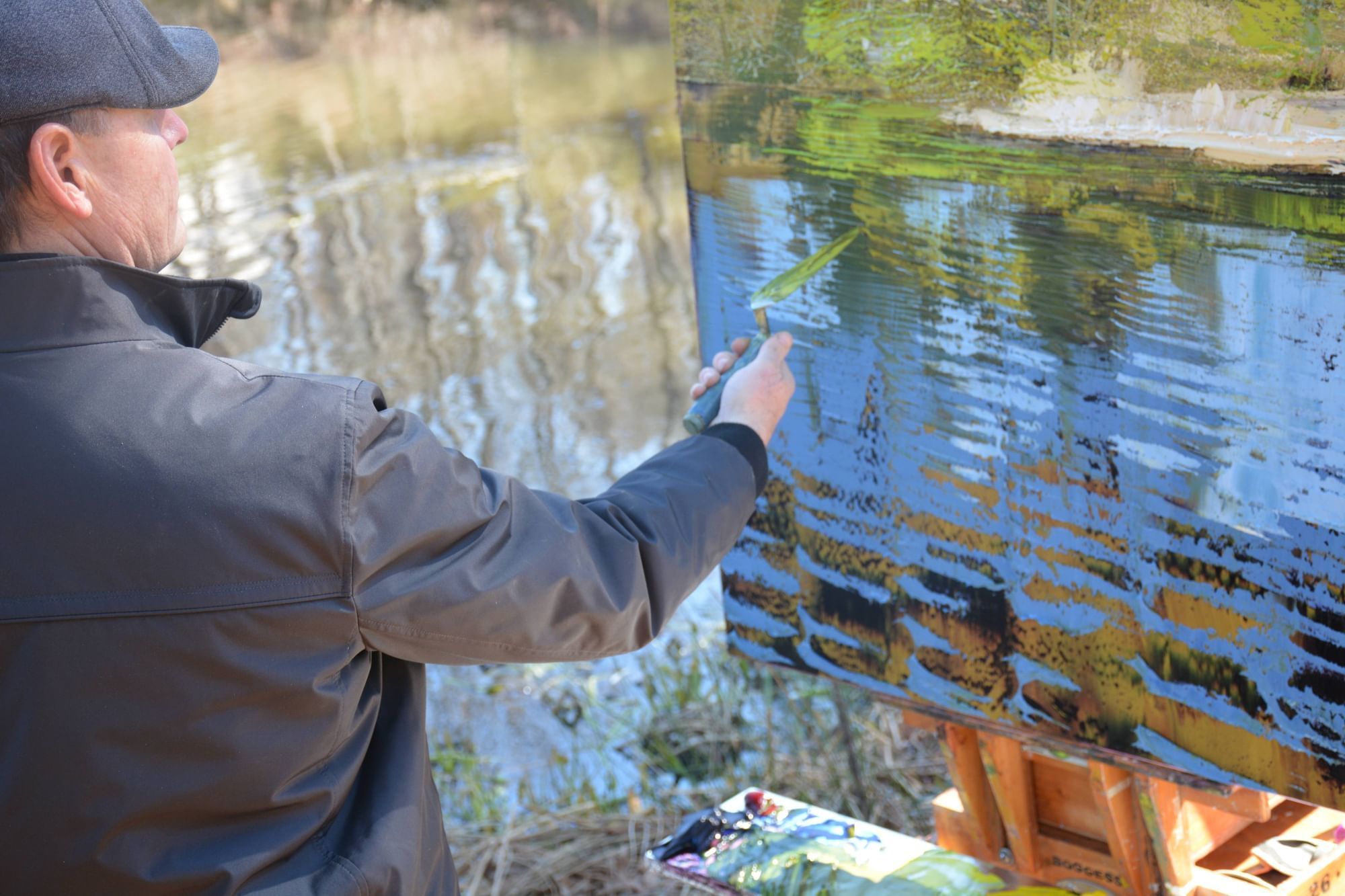 A man painting on a canvas by a river near Umstead Hotel and Spa