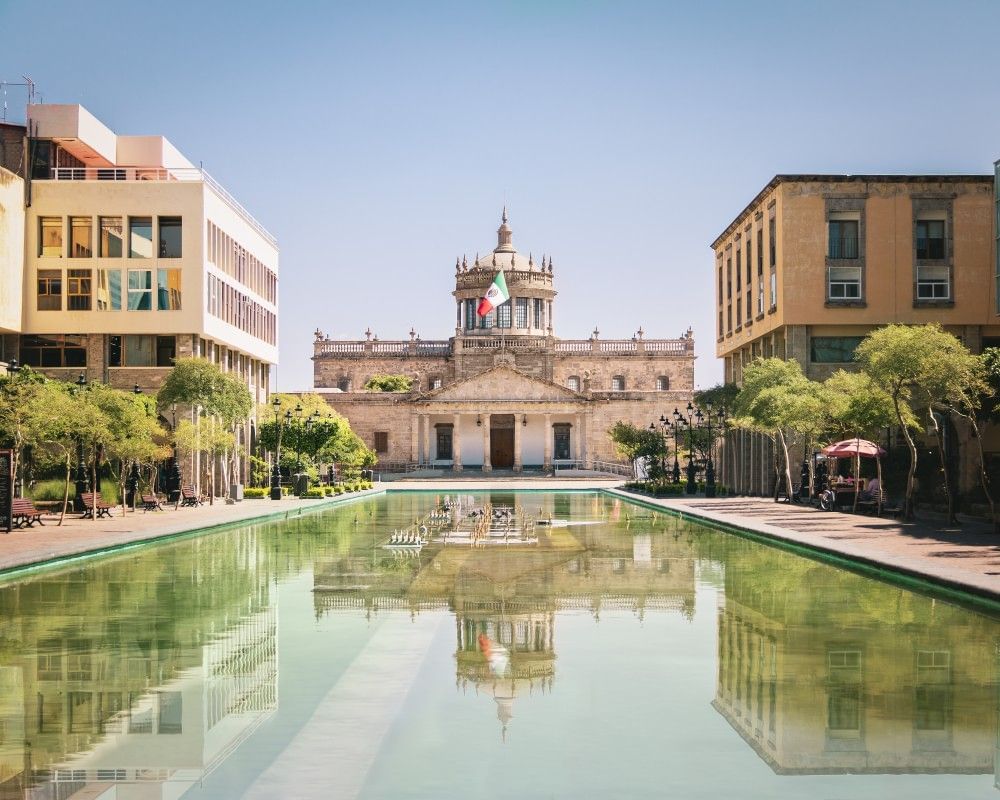 Hospicio Cabañas palace with a dome reflected in a long, still water fountain near Camino Real Pedregal Mexico