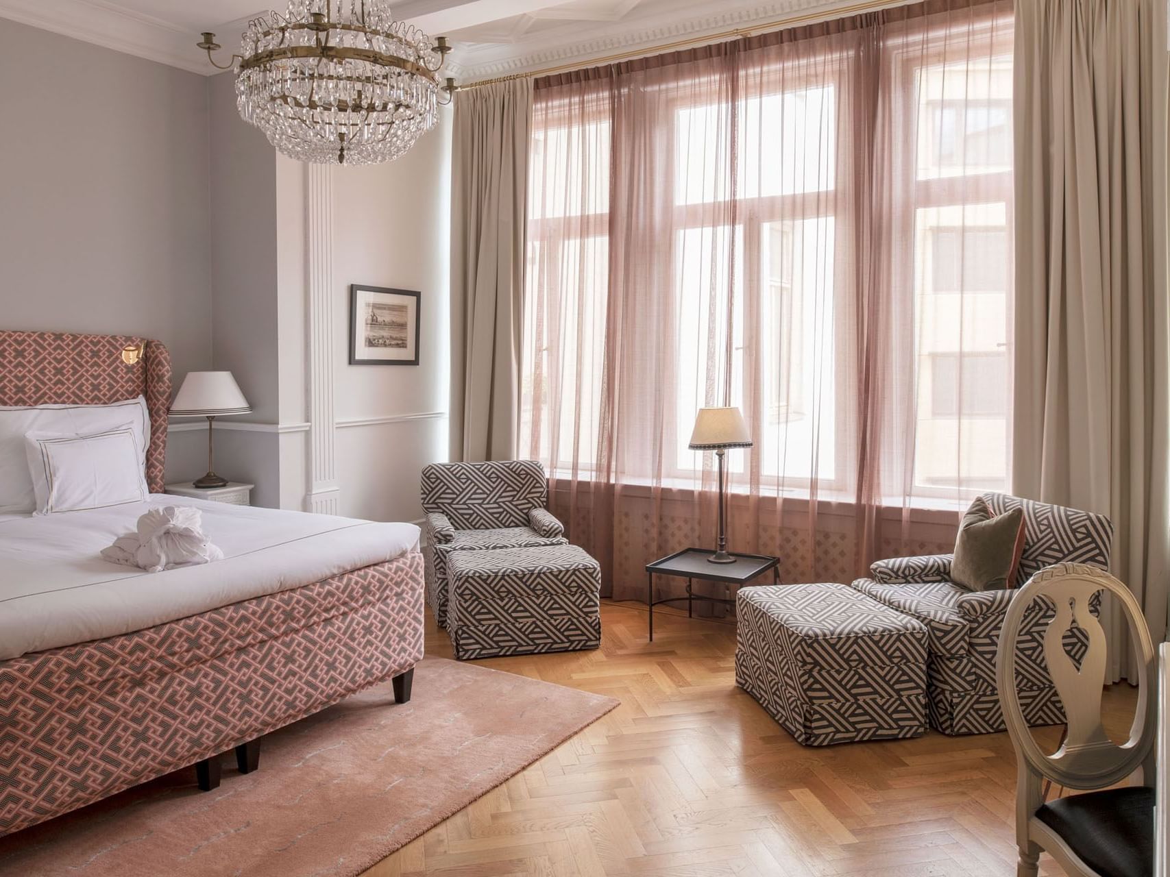 Work desk & lounge chairs facing king bed with a large window in the Deluxe Room at The Sparrow Hotel