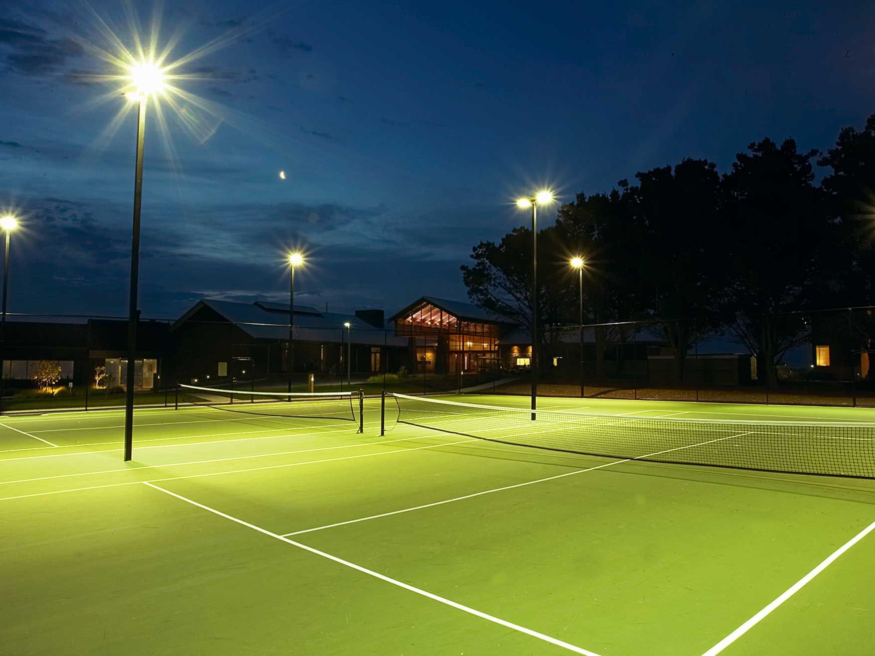 Lit tennis courts at night with lights on at Silverwater Resort