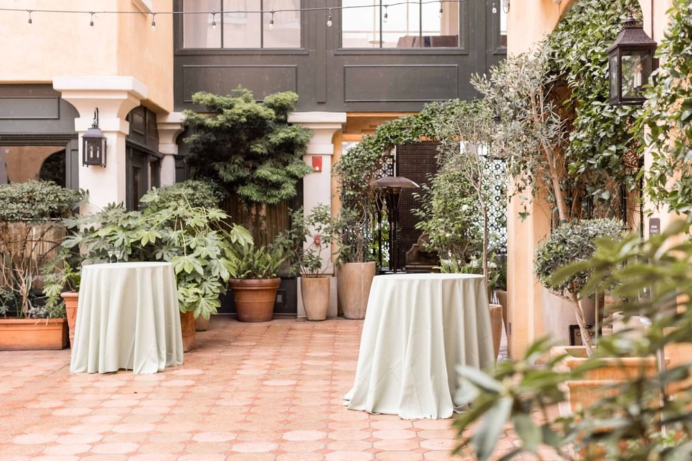 Beautiful outdoor courtyard surrounded by lush greenery, set for an event at El Prado Hotel