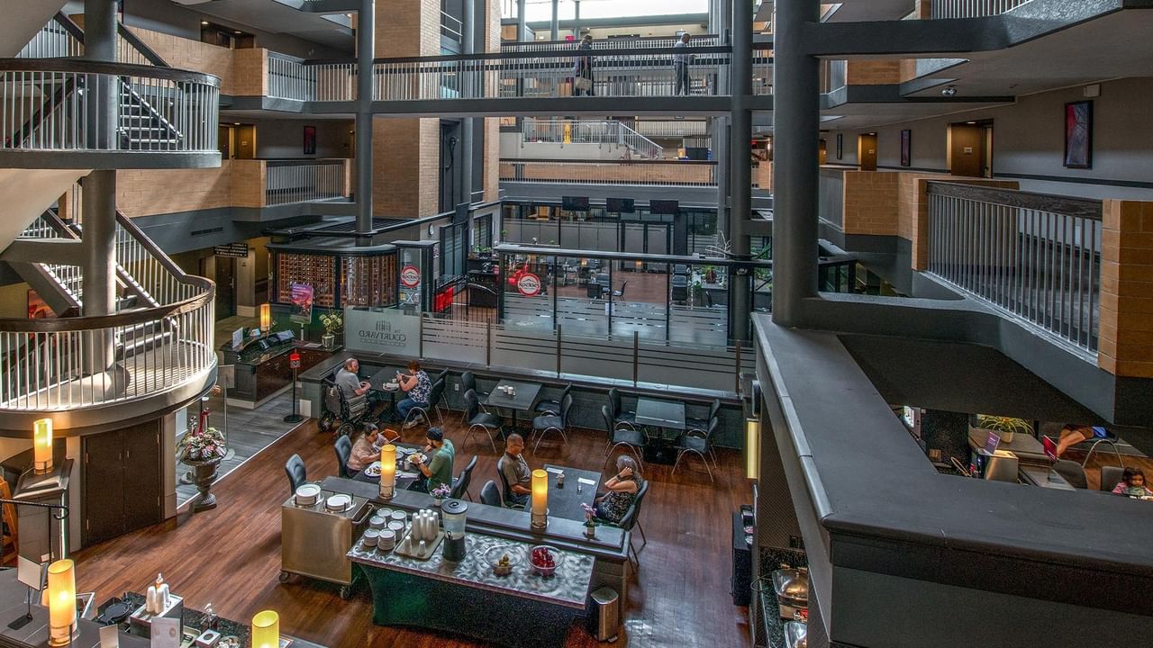Multi-level hotel atrium with wooden floors, seating areas, and floor-to-ceiling windows at Coast Calgary University Area Hotel by APA