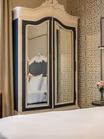 Large armoire by a white desk chair and bed under a patterned wallpaper in Superior Queen Room at Warwick San Francisco