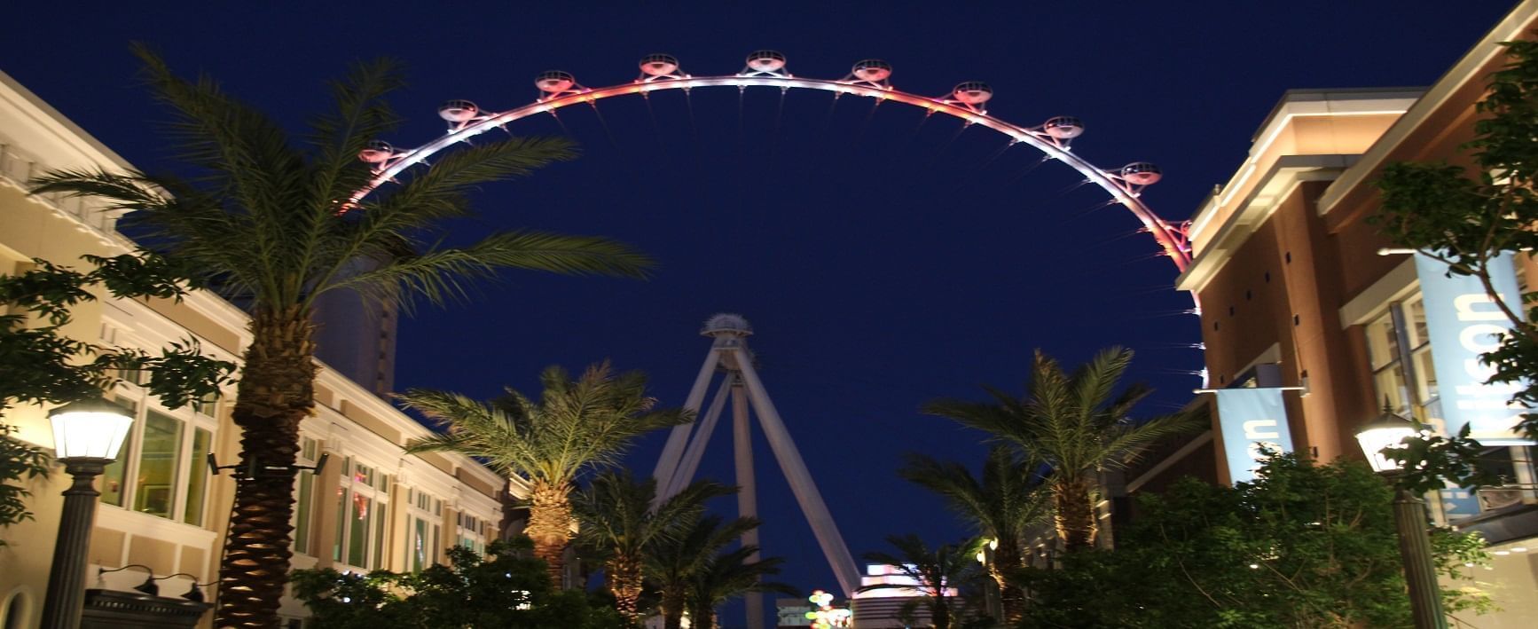 a nighttime view of a city street with a large Ferris wheel