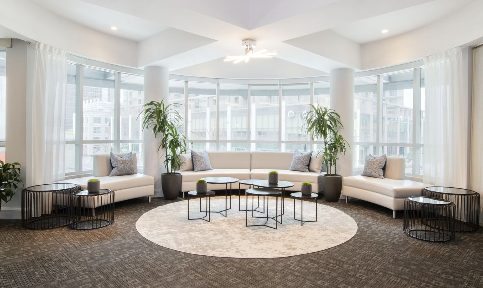 Modern white curved sofas and round black coffee tables at Warwick Le Crystal Montreal