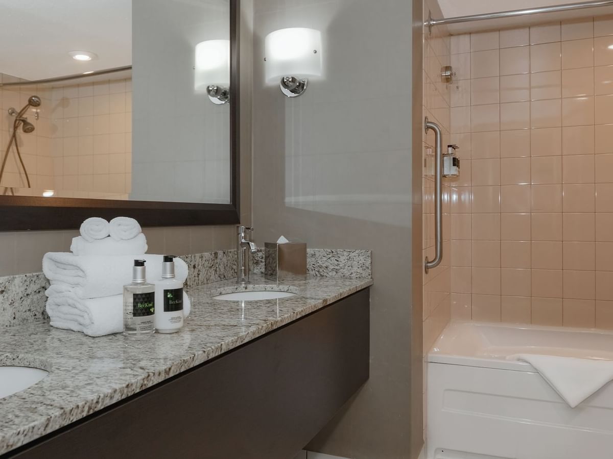 Hotel bathroom with bathtub, sink, soap, and towels.