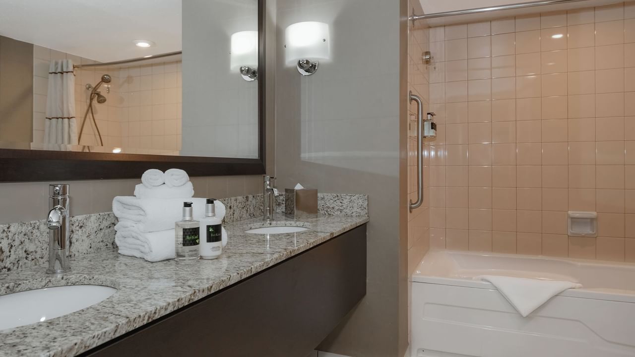 Hotel bathroom with bathtub, sink, soap, and towels.