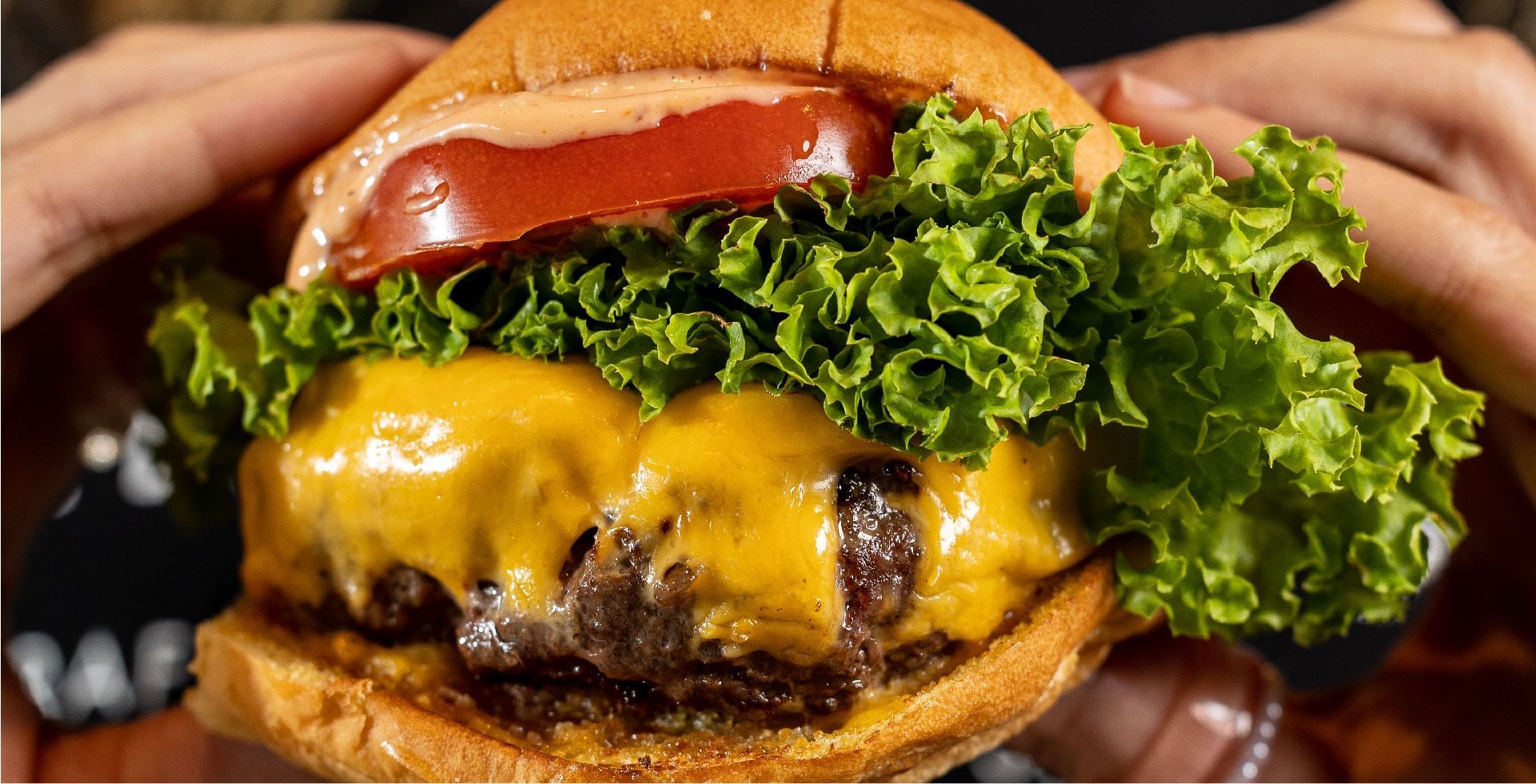 A large, gourmet burger with tomato and cheese, held at Sunway Resort