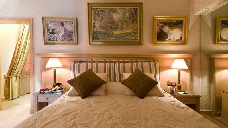 Bed with nightstand and paintings on the wall in Royal Suite at Warwick Brussels