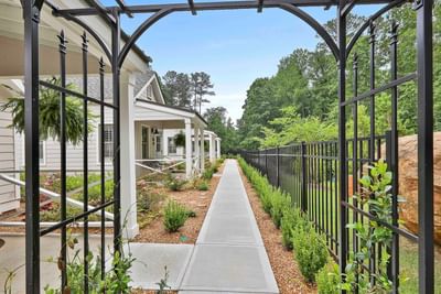 Close-up of black vine-covered archway in cottages at Laurel Brooke entrance surrounded by greenery on a sunny day