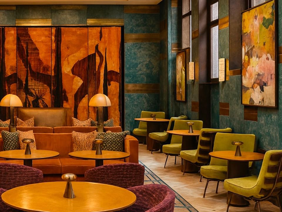 Armchairs around tables & sofa beside art screen in Lobby Lounge at Thompson Rome, highlighting panoramic restaurant in Rome