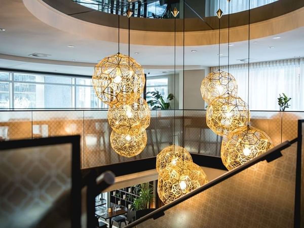 Golden sphere pendant lights hanging over a modern dining area at Warwick Le Crystal Montreal