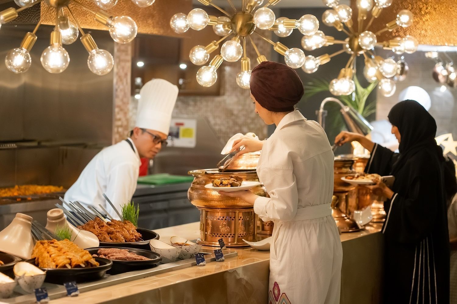 Two ladies serving food from the Iftar buffet in The Stage at Paramount Hotel Dubai