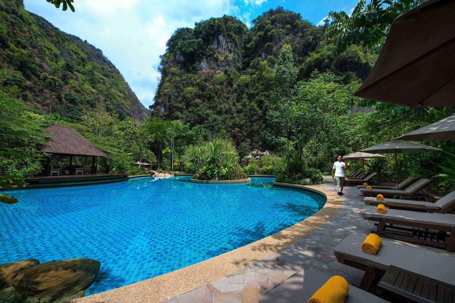Landscape view of sunbeds by the outdoor pool at The Banjaran Hotsprings Retreat