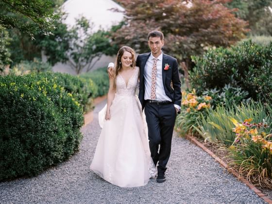 Groom & bride posing on a walking path in the garden with flowers at The Clifton