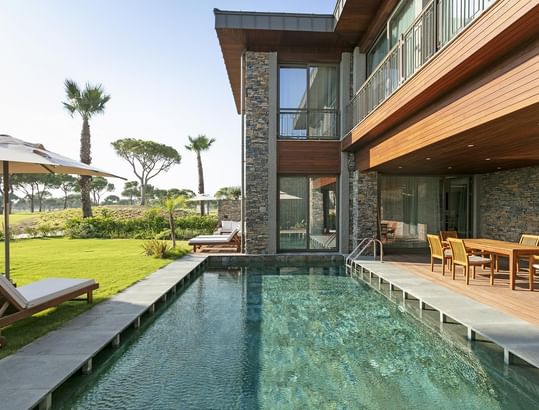 Cullinan Villa with a pool and wooden patio overlooking the green lawn at Cullinan Belek
