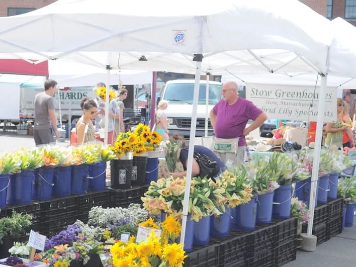 A woman looking at sunflowers in an outdoor flower stand.