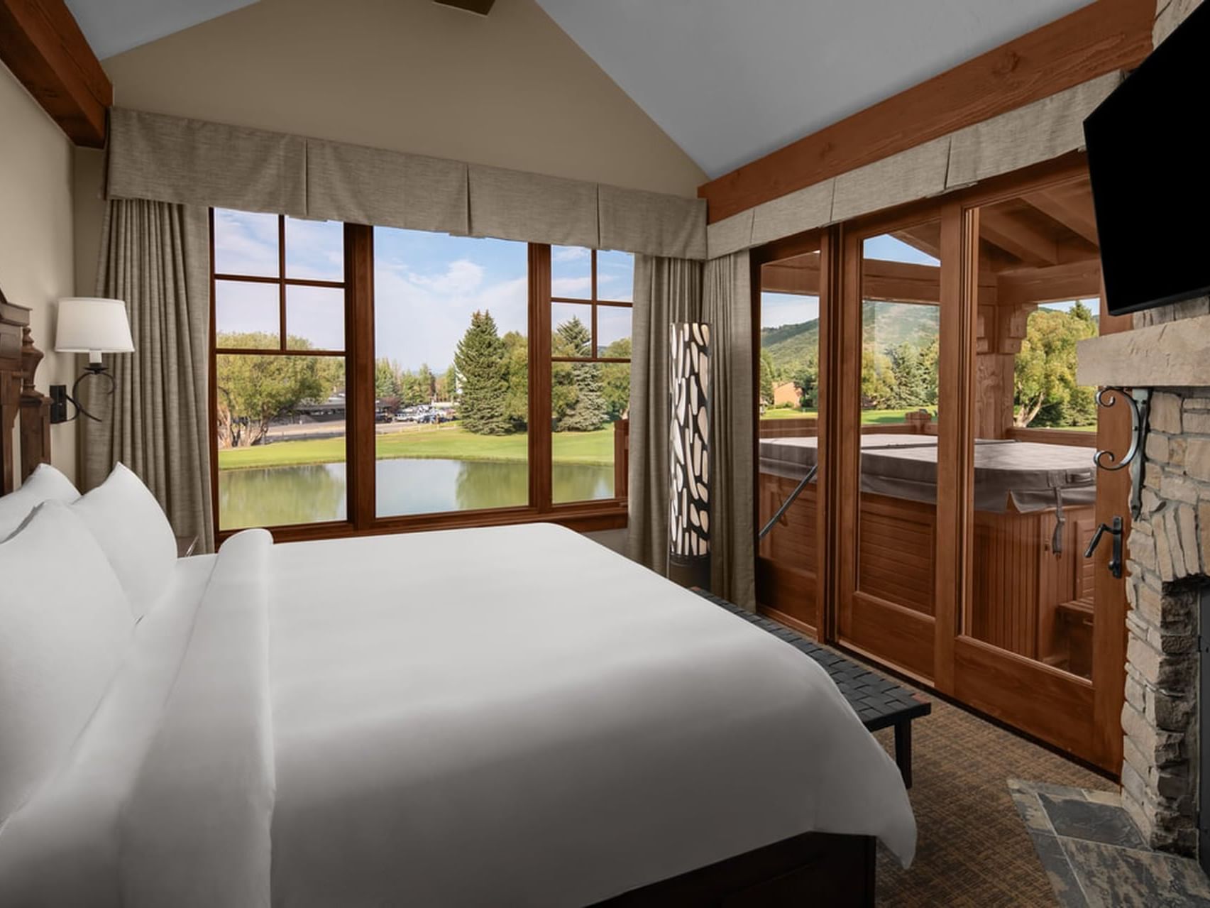 Cottage Deluxe Executive Suite with white bedding, exposed beams, and golf course views at Hotel Park City Autograph Collection.