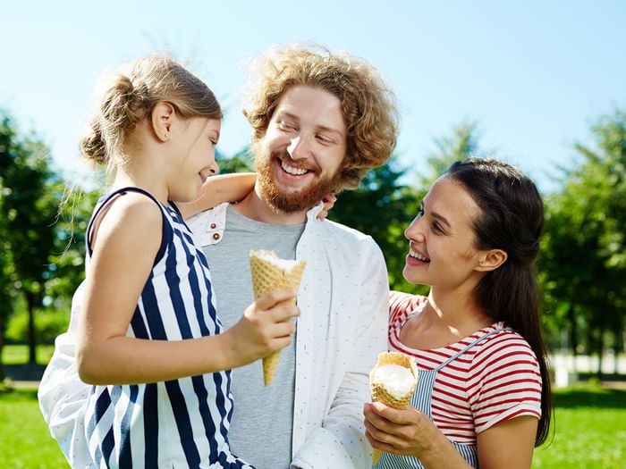A family of three eating ice cream in a park