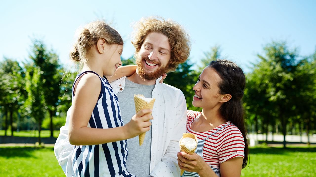 A family of three eating ice cream in a park