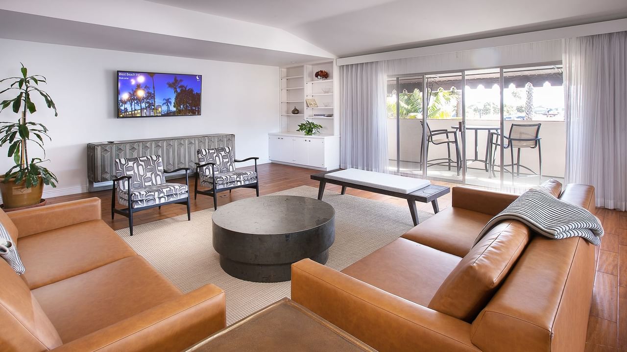 Living room with two couches, a coffee table, chairs, and a TV mounted on the wall.