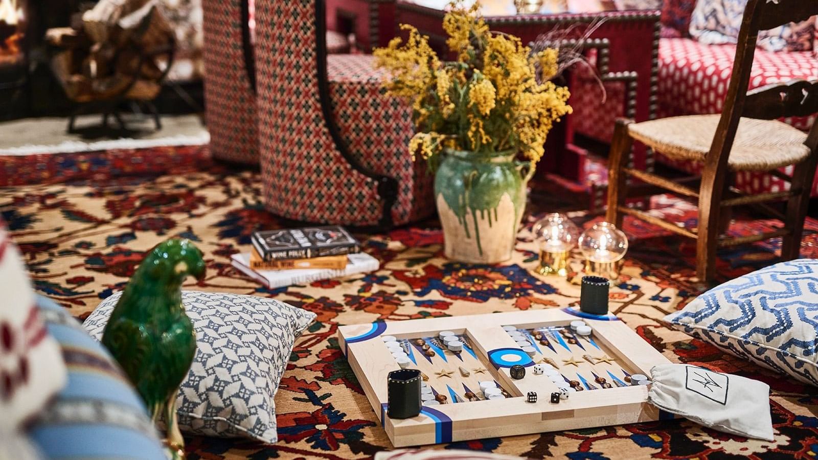 Backgammon board resting on a large patterned rug, surrounded by pillows and a vase of yellow flowers at Marbella Club