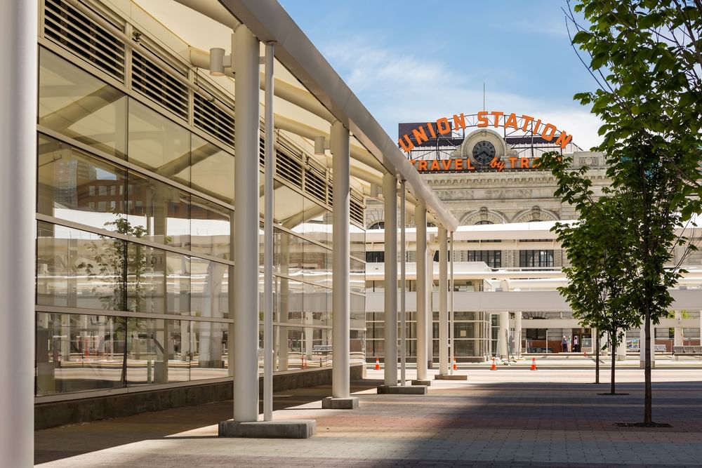 Modern glass and pillar walkway leading the eye to Denver's historic Union Station sign under a blue sky at Warwick Denver