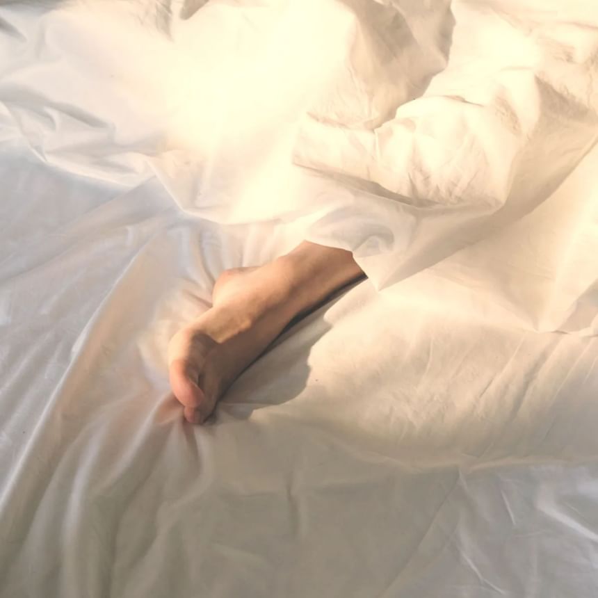 Close-up of leg under a sheet on a bed at Honeyrose Hotel