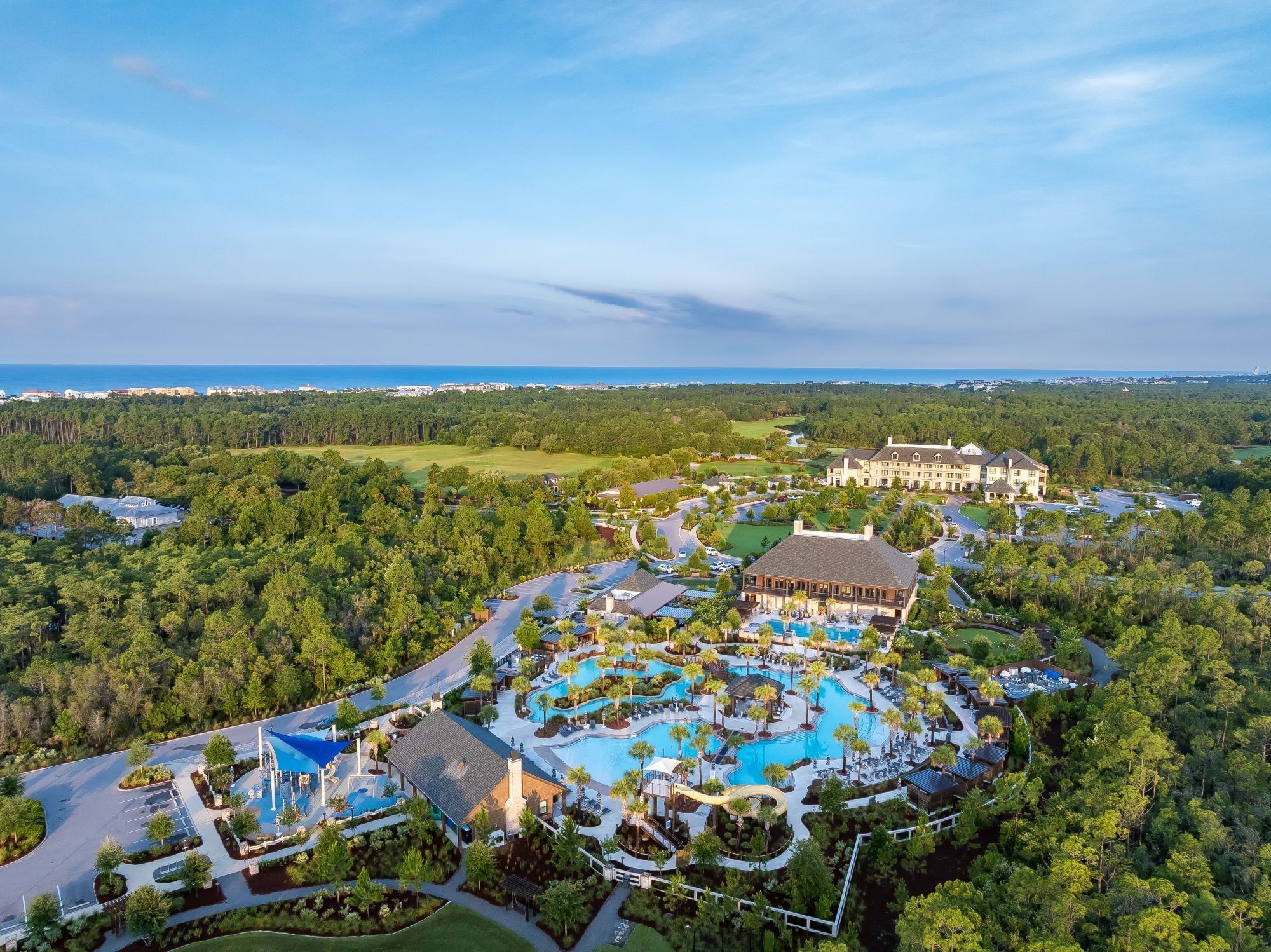 Aerial view of Camp Creek Inn with pools, a waterslide, the wellness center building, and the playground.