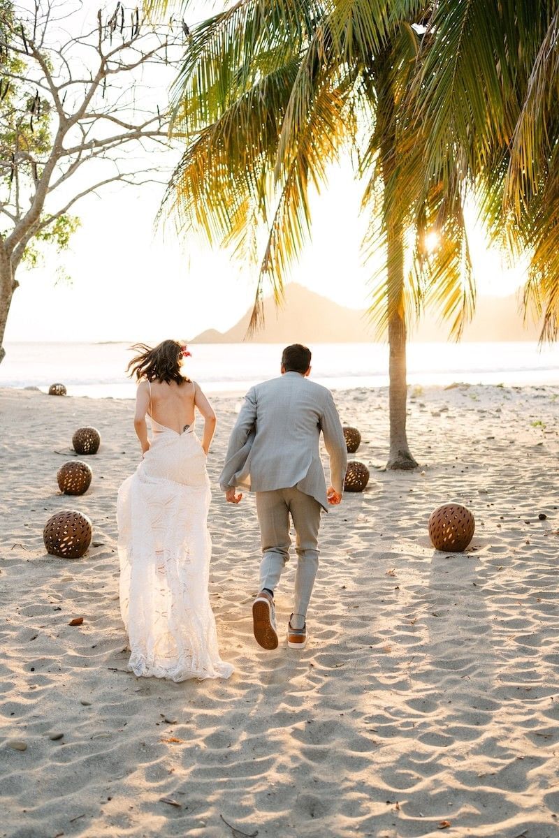 Couple running by palm trees on the sand at Morgan's Rock, a romantic eco resort Nicaragua with private plunge pools
