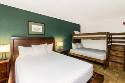 Queen bed & twin-sized bunk bed with nightstand in Family Suite at Boothill Inn & Suites