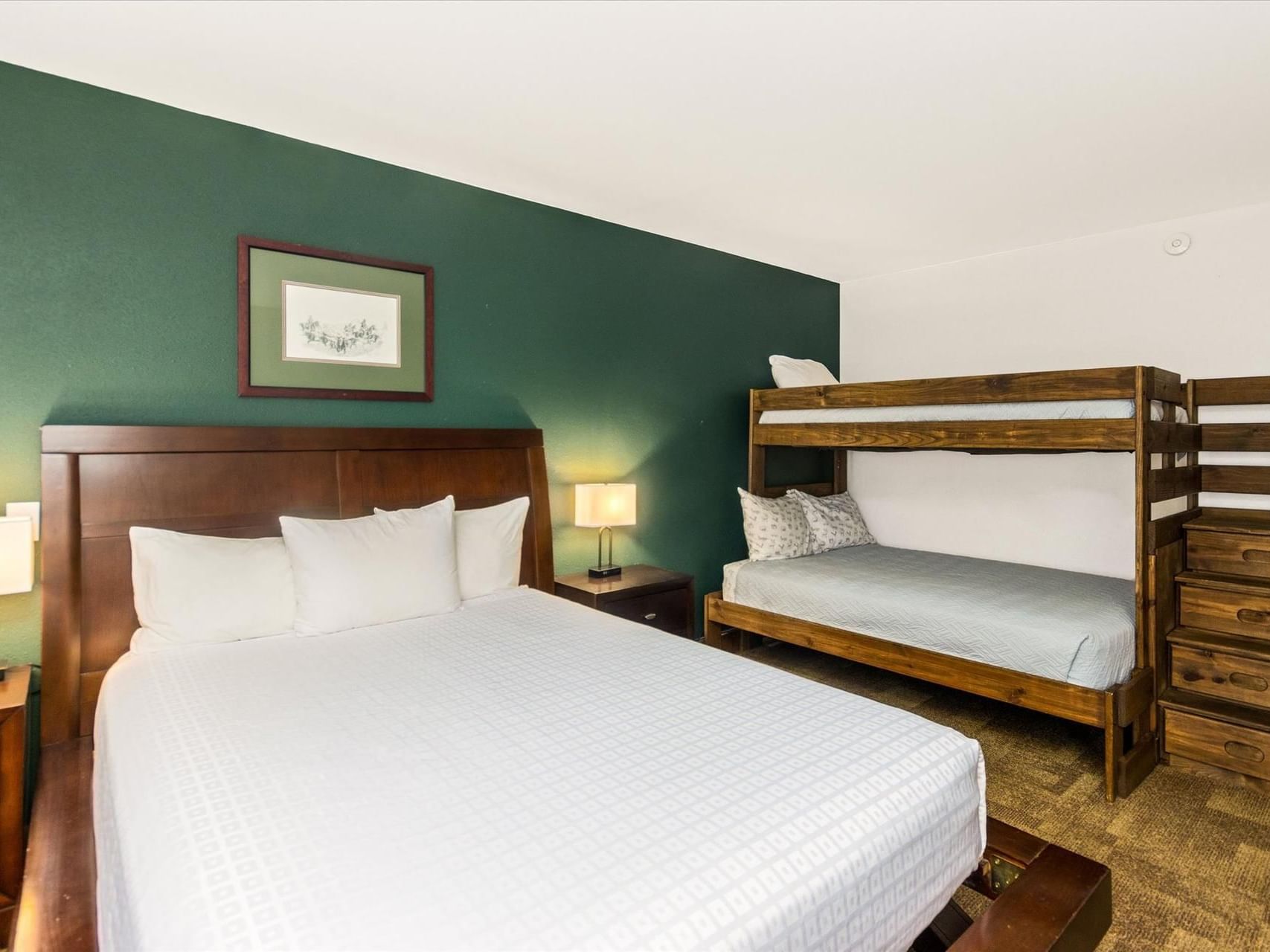 Queen bed & twin-sized bunk bed with nightstand in Family Suite at Boothill Inn & Suites