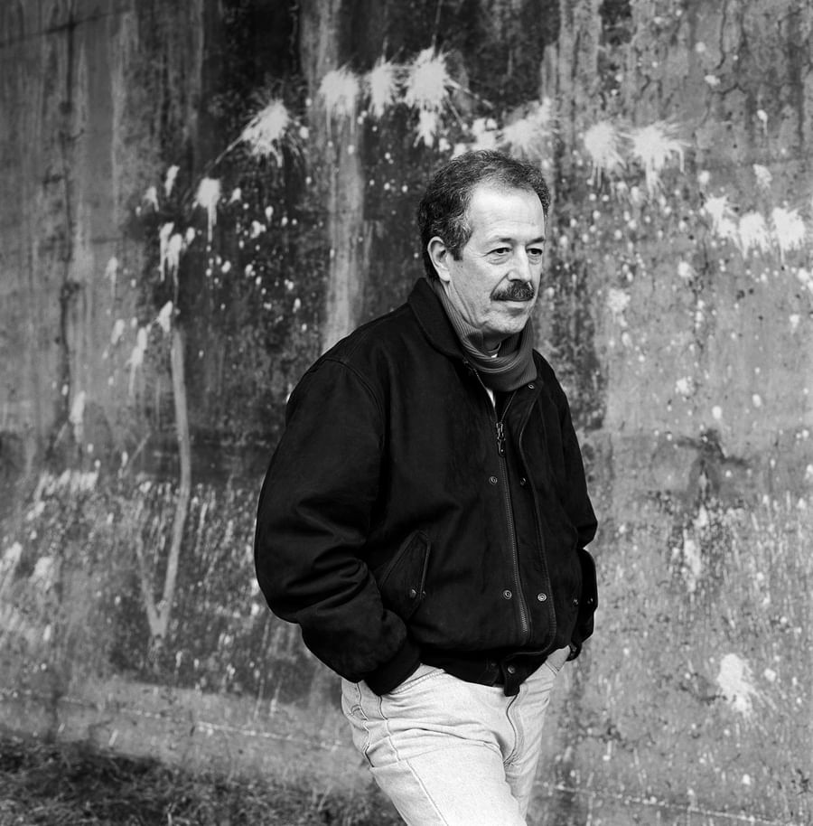 Man in black jacket standing against weathered concrete wall in black and white portrait at Warwick Le Crystal Montreal