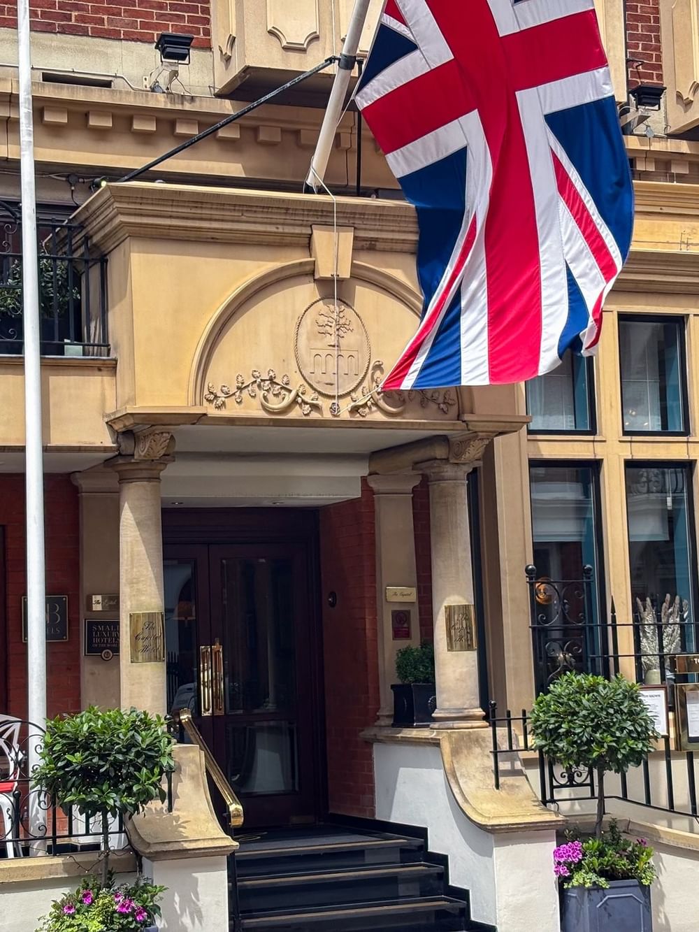 Elegant hotel entrance with Union Jack flag and outdoor seating at The Capital Hotel.