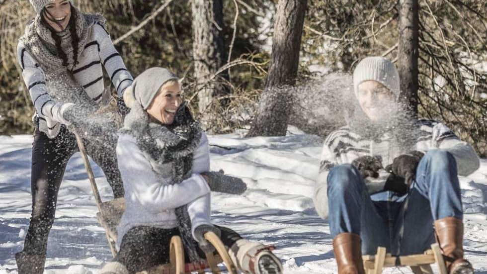 Three people enjoying a snowy hill near Falkensteiner Hotel Kronplatz