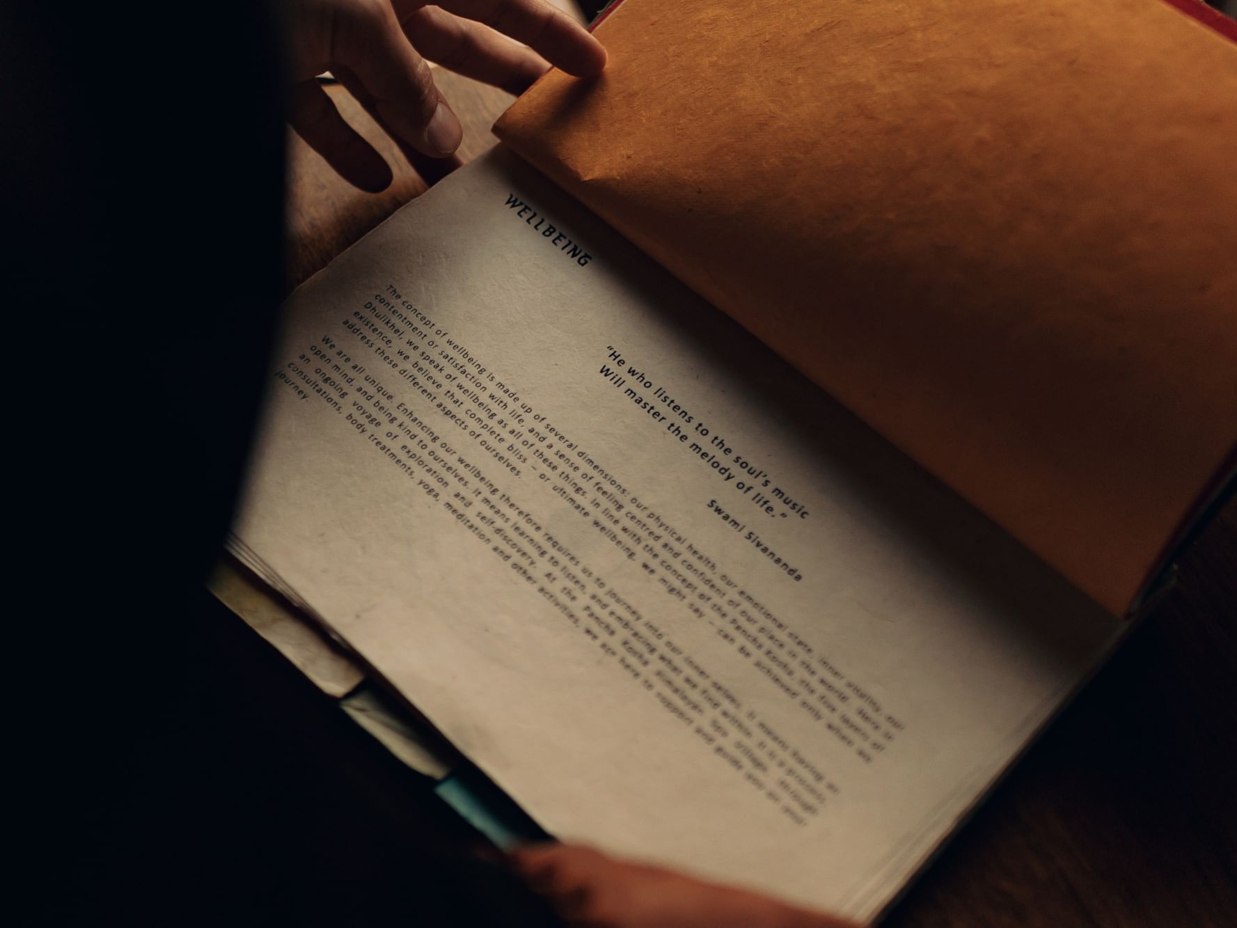 Close-up of a hand holding a page from a book titled Wellbeing at Dwarika's Himalayan Wellbeing