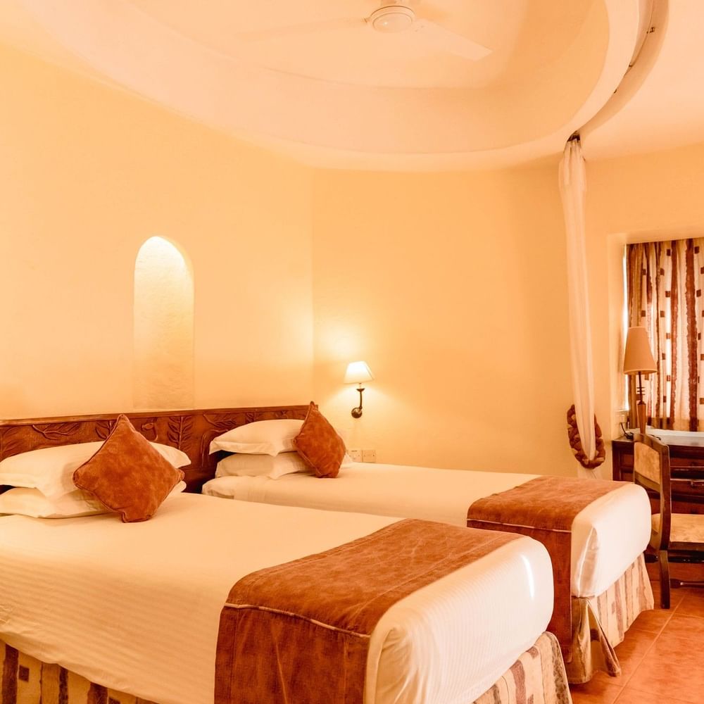 Two neatly made beds in a Standard Twin Room at Arusha Serena Hotel in Arusha.