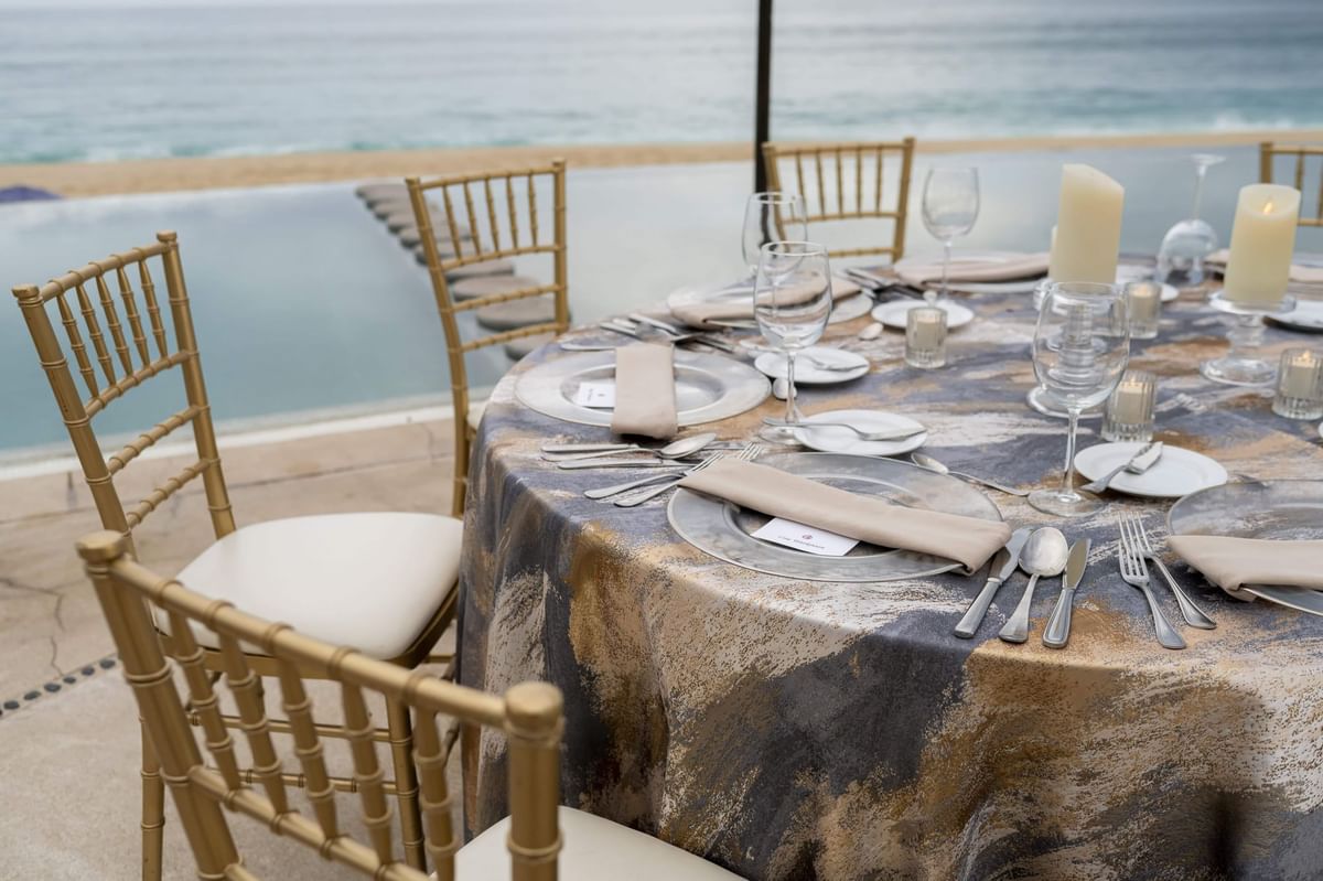 Elegantly set outdoor dining table with ocean views by the pool at Marquis Los Cabos Resort