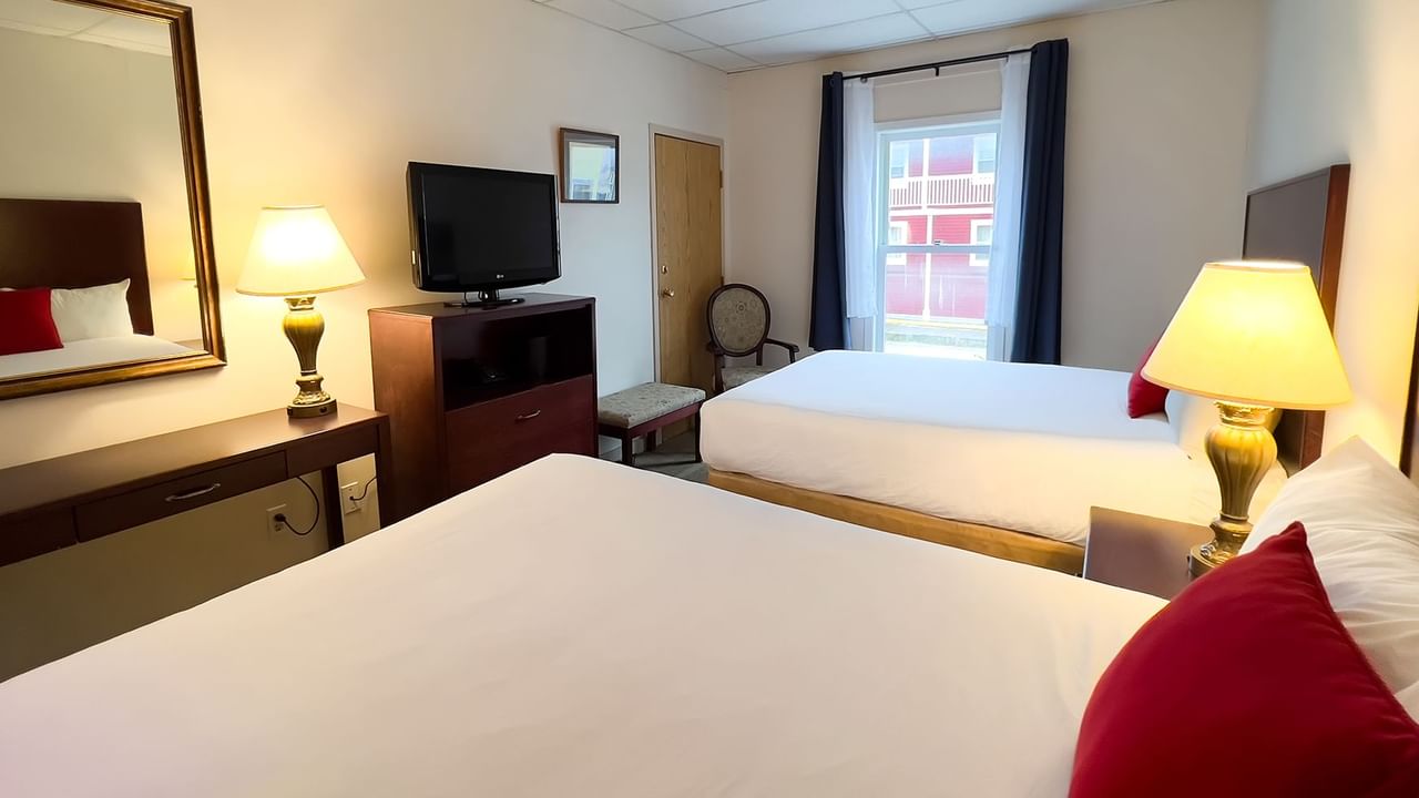 Hotel bedroom with two queen beds, tv, chair, mirror, and lamp