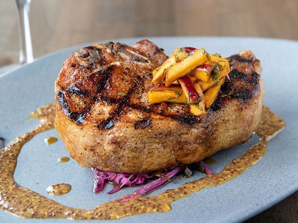 Beautifully grilled pork chop with a vibrant fruit salsa served in Apropos Restaurant & Bar at The Abbey Inn & Spa
