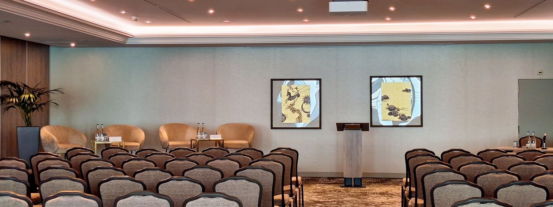 Mont-Blanc + Jura featuring Tan chairs surrounding a long table by a modern red wall panel at Warwick Geneva