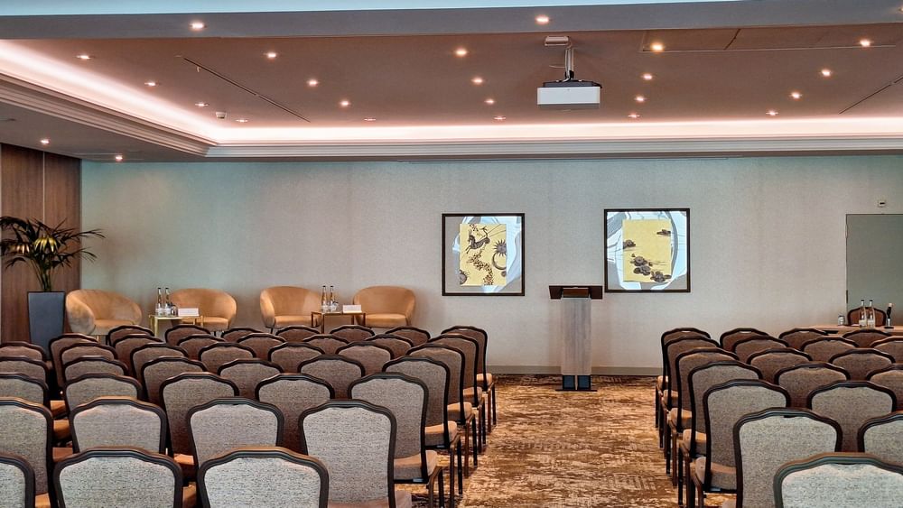 Mont-Blanc + Jura featuring Tan chairs surrounding a long table by a modern red wall panel at Warwick Geneva